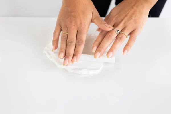 A pair of hands rolling out clay with a small roller.
